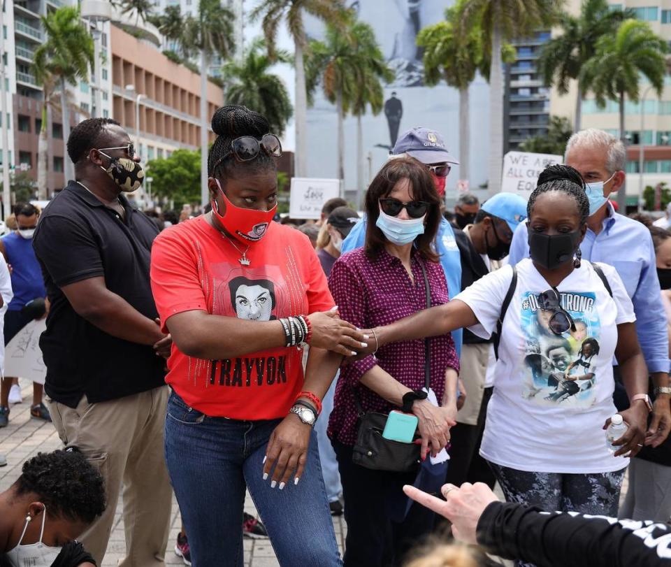 Sybrina Fulton, left, mother of Trayvon Martin, prepares to bow her head in prayer while standing next to State Attorney Katherine Fernández Rundle, center, during a multi-faith rally against police brutality at the Torch of Friendship on Sunday, June 14, 2020.