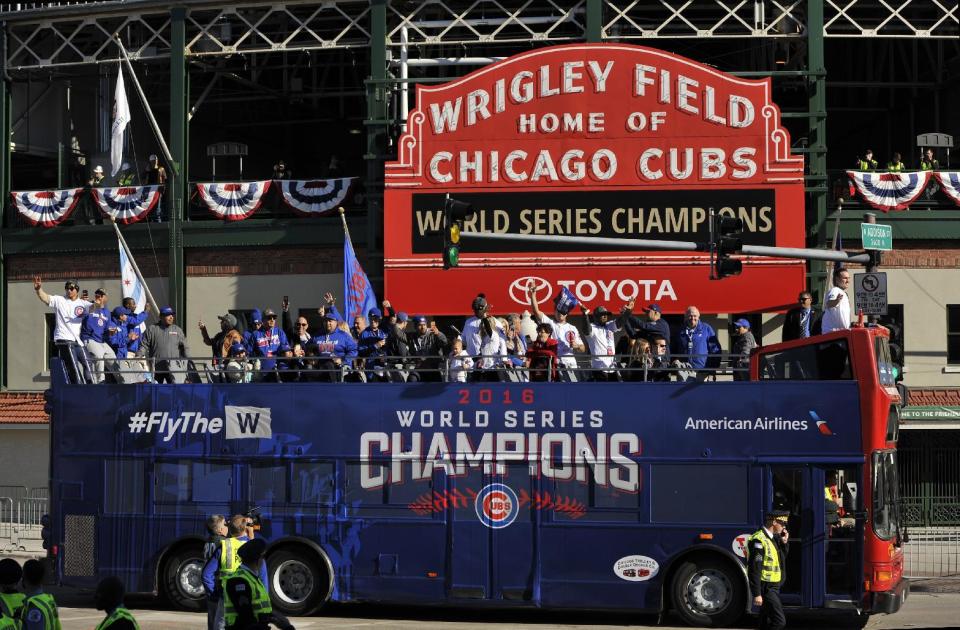 FILE - In this Nov. 4, 2016, file photo, a bus carrying Chicago Cubs players, family and friends passes Wrigley Field during a parade honoring the World Series champion baseball team in Chicago. The Cubs’ first World Series title since 1908 is the runaway winner for top sports story of 2016. (AP Photo/Paul Beaty, File)