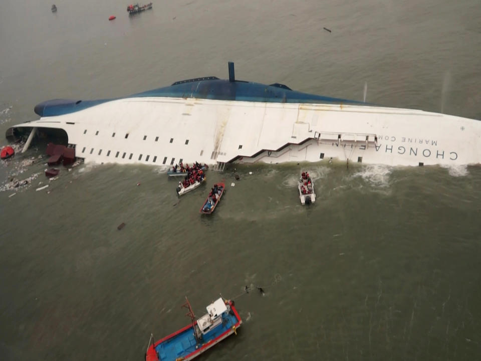 FILE - In this April 16, 2014 file photo, released by South Korea Coast Guard via Yonhap News Agency, South Korean rescue team boats and fishing boats try to rescue passengers of the sinking Sewol ferry, off South Korea's southern coast,near Jindo, south of Seoul. It is a decision that has maritime experts stumped and is at odds with standard procedure: Why were the passengers of the doomed South Korean ferry told to stay in their rooms rather than climb on deck? Evacuations can be chaotic and dangerous, and an important principle in maritime circles is that even a damaged ship may be the best lifeboat. But car ferries like the Sewol, which left some 300 people missing or dead when it sank Wednesday, are different. They are particularly susceptible to rapid capsizing which makes it critically important that the crew quickly evacuate passengers when there is trouble. (AP Photo/South Korea Coast Guard via Yonhap, File) KOREA OUT