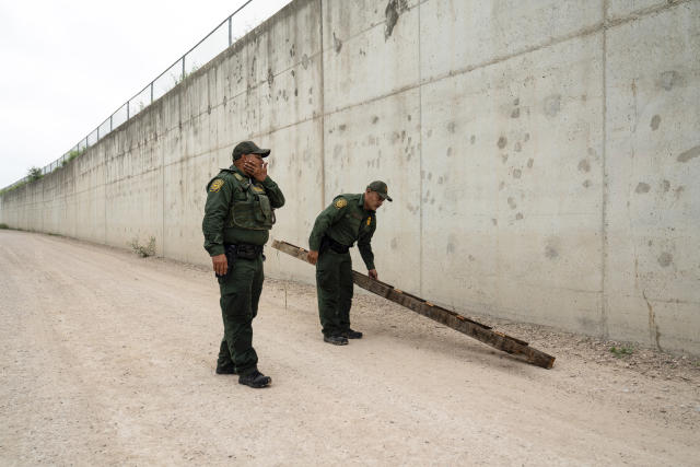 U.S. Border Patrol agents pick up a ladder that migrants carried to the border wall near the port of entry in Hidalgo, Texas, Thursday, May 4, 2023. (AP Photo/Veronica G. Cardenas)