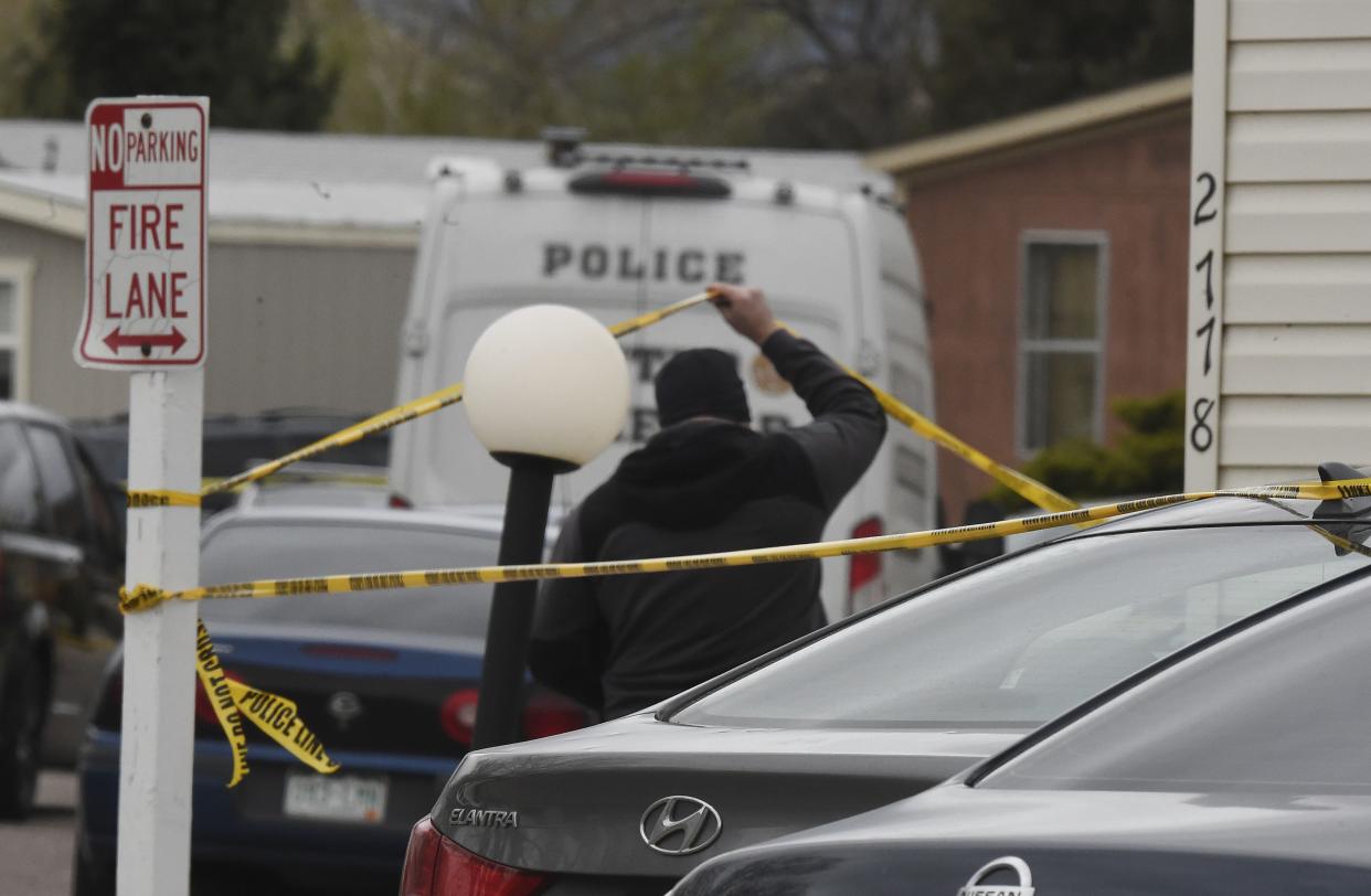 A Colorado Springs Police Department officer lifts up crime tape at the scene where multiple people were shot and killed early Sunday, May 9, in Colorado Springs, Colo. 