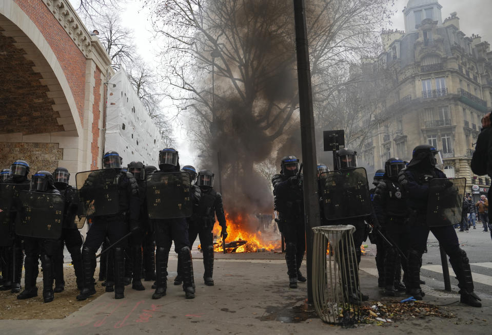 Police officers stand next to burning barricade during a demonstration in Paris, Saturday, March 11, 2023. Opponents of President Emmanuel Macron's hotly contested plan to raise the retirement age from 62 to 64 were taking to the streets of France on Saturday for the second time this week in what union's hope will be a new show of force meant to push the government to back down. (AP Photo/Lewis Joly )