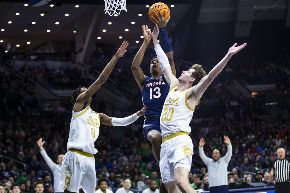 Virginia's Ryan Dunn (13) tries to drive between Notre Dame's Markus Burton (3) and J.R. Konieczny (20) during the first half of an NCAA college basketball game on Saturday, Dec. 30, 2023, in South Bend, Ind. (AP Photo/Michael Caterina)