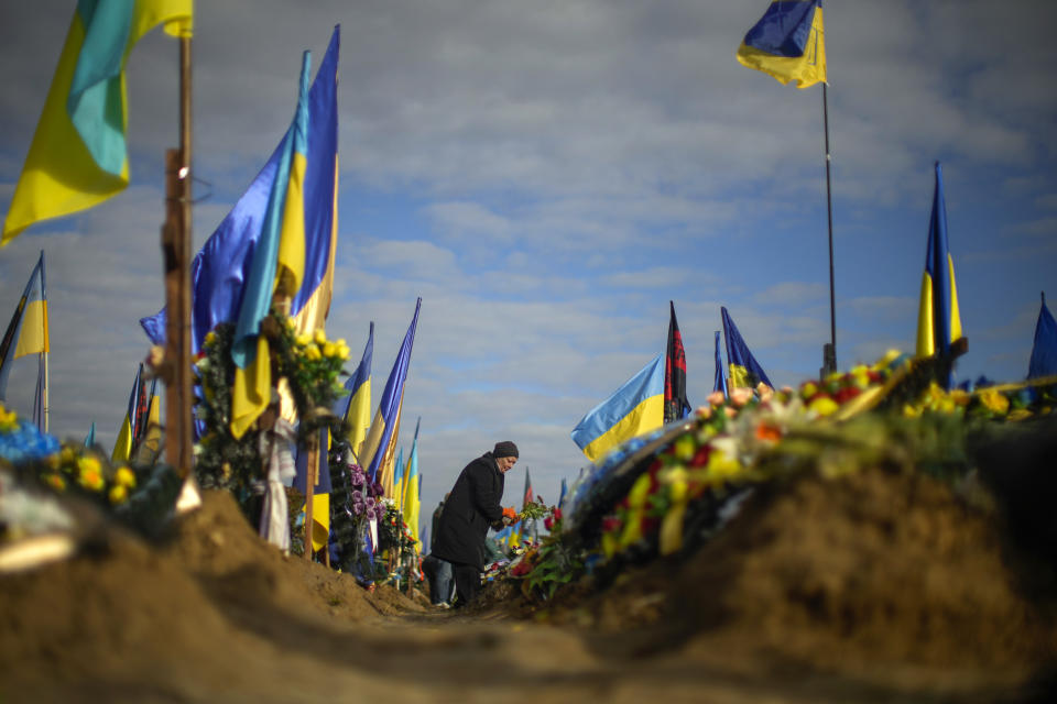 Olga places flowers on the grave of a relative recently killed on military duty, in a cemetery during Ukraine Defenders Day in Kharkiv, Ukraine, Friday, Oct. 14, 2022. (AP Photo/Francisco Seco)