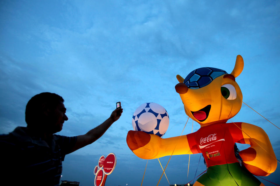 A man takes pictures of the mascot of the 2014 World Cup soccer tournament in Brasilia, Brazil, Monday, Sept. 24, 2012. The mascot is a yet to-be-named Brazilian endangered armadillo. FIFA said Brazilians will have until mid-November to choose the mascot's name from three choices: Amijubi, Fuleco and Zuzeco. (AP Photo/Eraldo Peres)