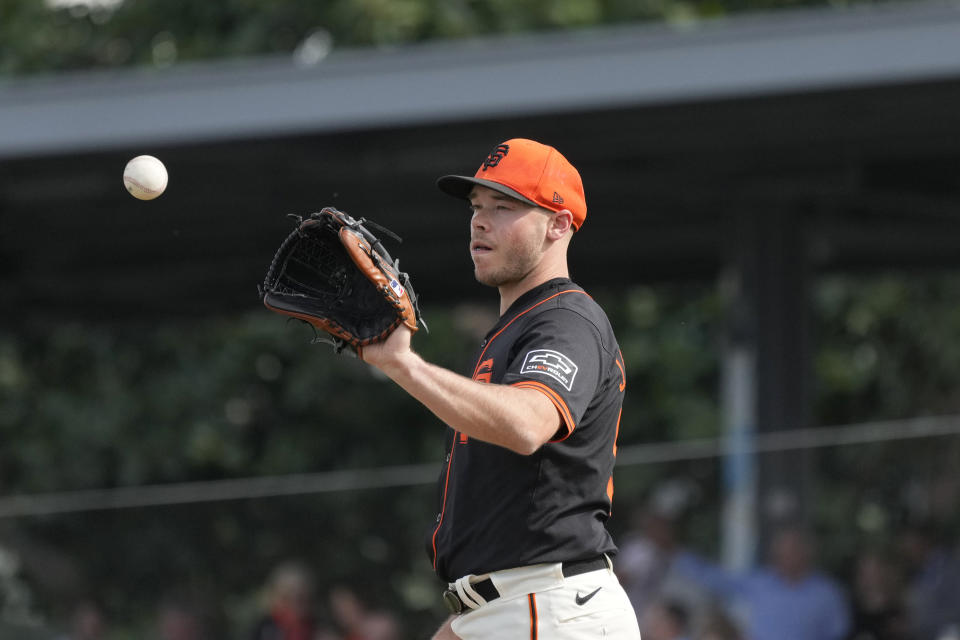 San Francisco Giants pitcher Daulton Jefferies reaches out for the baseball after warming up during the fifth inning of a spring training baseball game against the Seattle Mariners Tuesday, Feb. 27, 2024, in Scottsdale, Ariz. Jefferies is trying to come back from a second Tommy John surgery at age 28. (AP Photo/Ross D. Franklin)