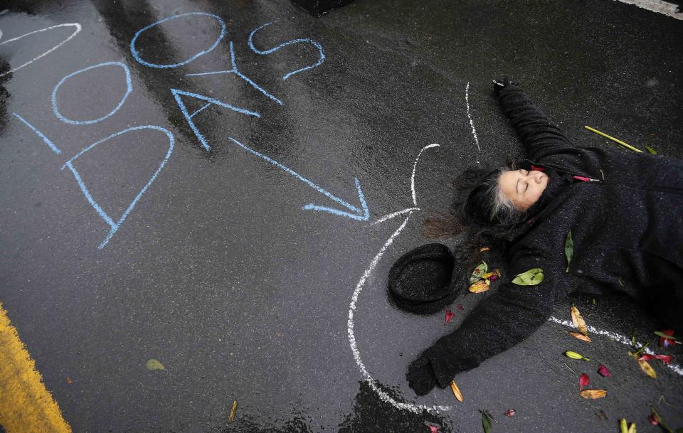 A demonstrator lays on the ground with a chalk outline representing a mock crime scene during a protest marking the 100th day since the shooting death of Michael Brown in St. Louis