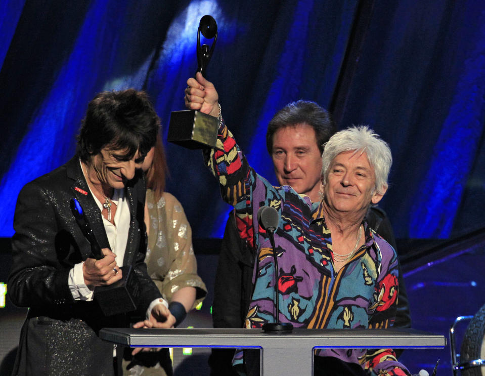 Ian McLagan, right, holds up his trophy after he and Ron Wood, left, and Kenney Jones, background, were inducted into the Rock and Roll Hall of Fame as members of the Small Faces/Faces Saturday, April 14, 2012, in Cleveland. (AP Photo/Tony Dejak)