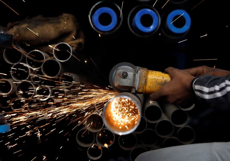 A worker cuts a metal pipe at a workshop in an industrial area in the old quarters of Delhi