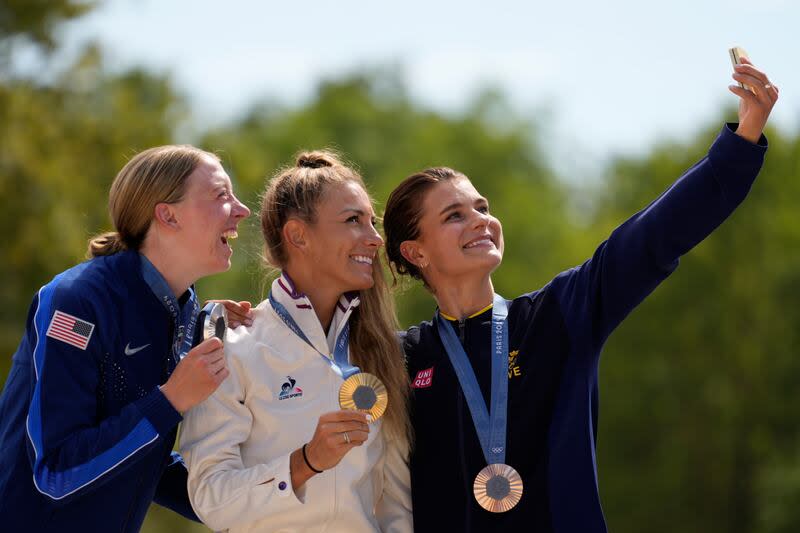 Pauline Ferrand Prevot, of France, centre, winner of the women's mountain bike cycling event, shows her gold medal flanked by silver medallist Haley Batten, of United States, left, and bronze medallist Jenny Rissveds, of Sweden, at the 2024 Summer Olympics, Sunday, July 28, 2024, in Elancourt, France. | George Walker IV