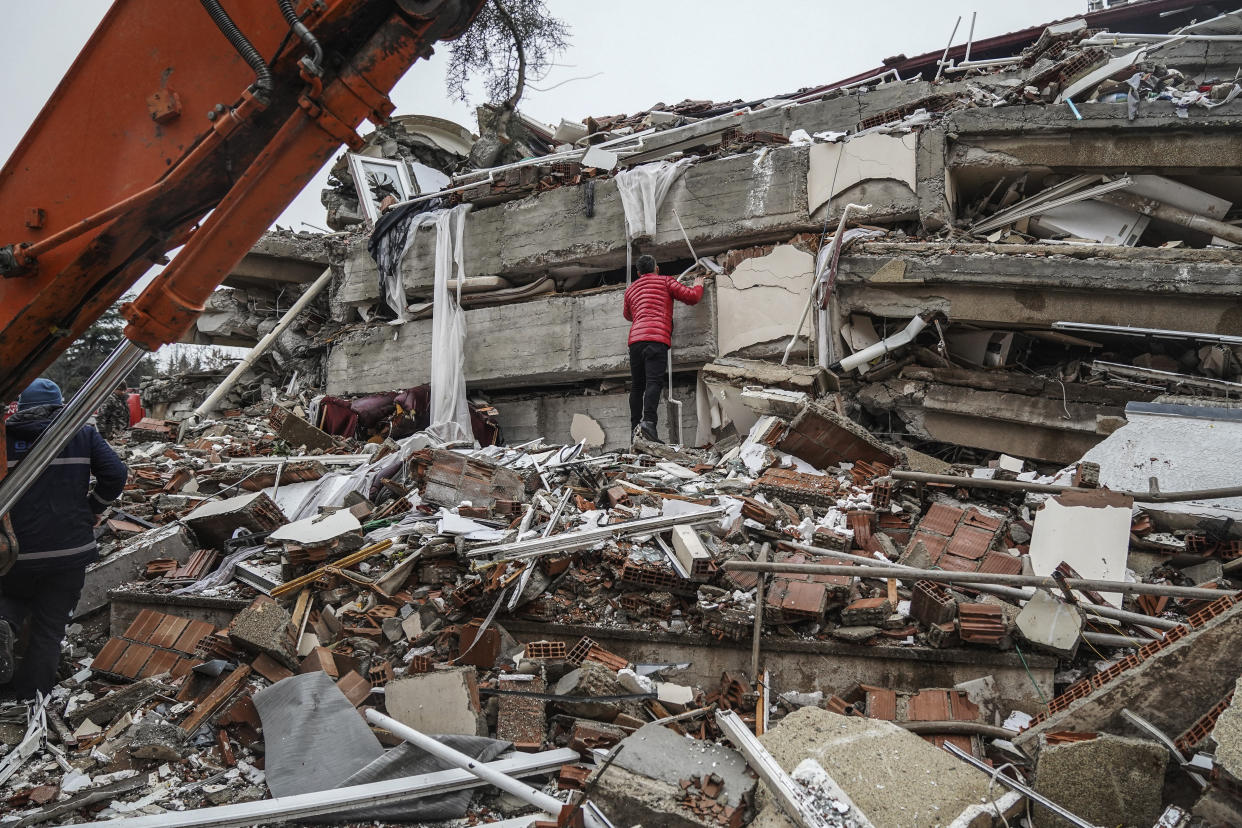 A man searches for people in the rubble of a destroyed building in Gaziantep, Turkey, Monday, Feb. 6, 2023. A powerful quake has knocked down multiple buildings in southeast Turkey and Syria and many casualties are feared. (AP Photo/Mustafa Karali)