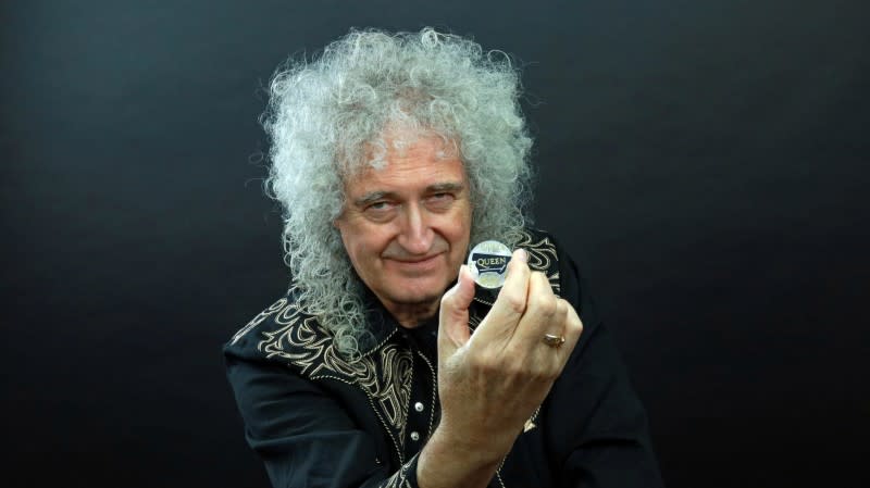 Guitarist Brian May of band Queen poses with a 5-pound coin