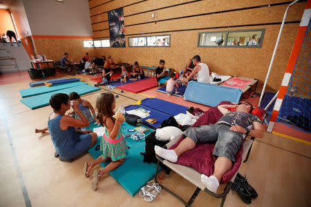 Tourists who were evacuated due to a forest fire, eat a meal and rest in a gymnasium in Bormes-les-Mimosas, in the Var department, France, July 26, 2017. REUTERS/Jean-Paul Pelissier