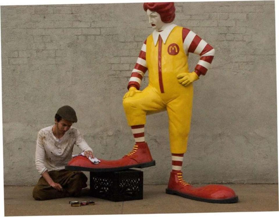 Jour 16 - New York (oeuvre mobile) - "Une réplique de Ronald McDonald se fait cirer les chaussures par un véritable garçon. La sculpture se baladera sur les différents trottoirs où se trouve le fast-food, et se placera en face de l'un d'eux à chaque heure de repas la semaine prochaine"  <a href="http://www.banksyny.com/" target="_blank">Banksy </a>