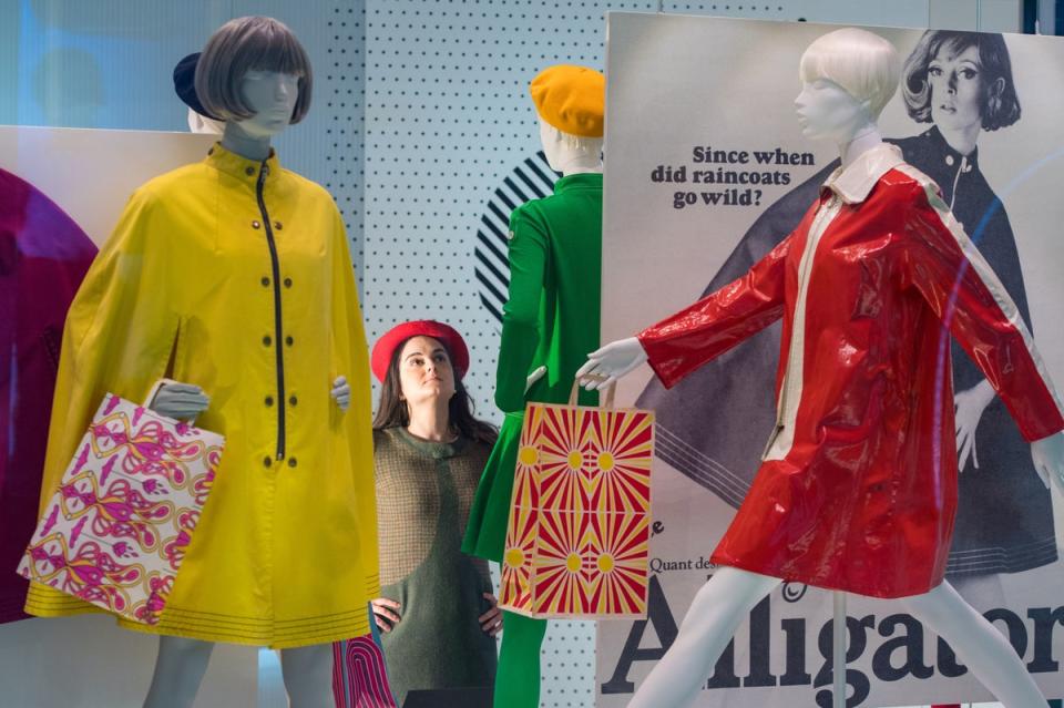 A gallery assistant checking a display of rain capes from 1967 during a preview of the Mary Quant exhibition at the V&A in 2019 (PA)