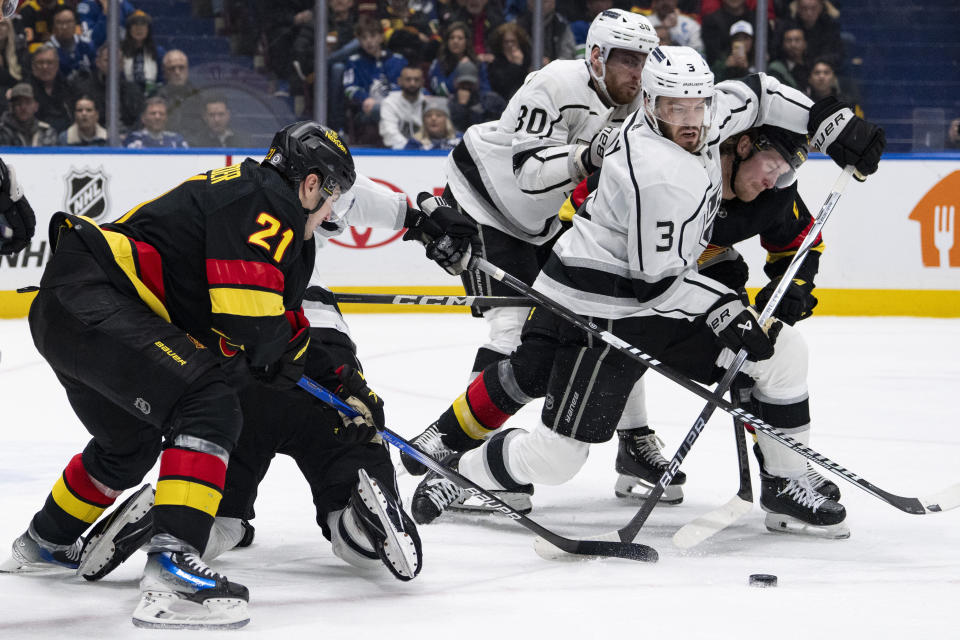 Vancouver Canucks' Nils Hoglander (21) and Brock Boeser (6) and Los Angeles Kings' Pierre-Luc Dubois (80) and Matt Roy (3) all vie for the puck during the third period of an NHL hockey game Thursday, Feb. 29, 2024, in Vancouver, British Columbia. (Ethan Cairns/The Canadian Press via AP)