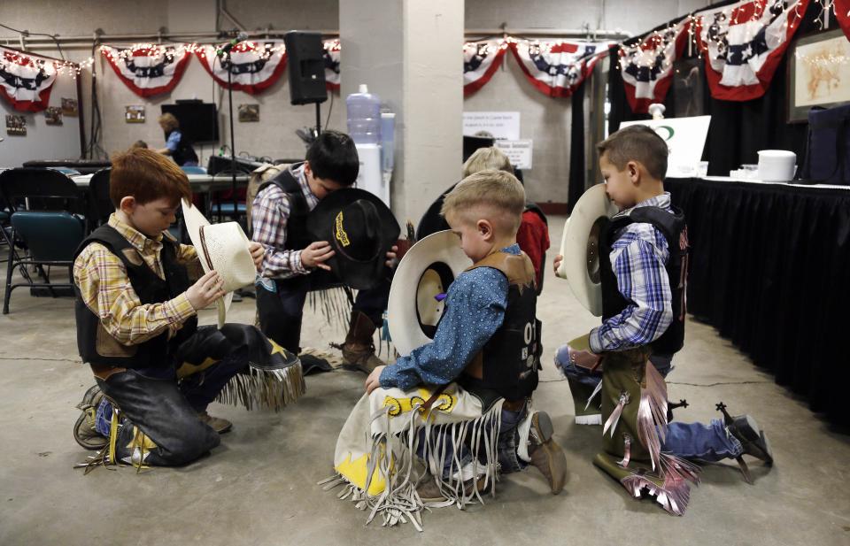 Boys set to compete in the mini bull riding competition kneel and pray before entering the arena at the 108th National Western Stock Show in Denver