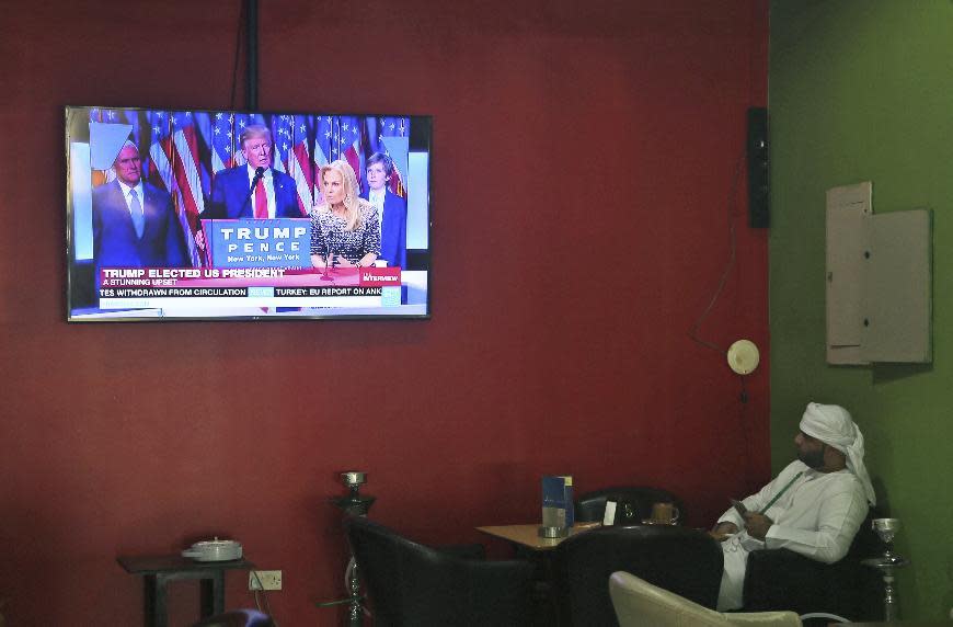 FILE - In this Thursday, Nov. 10, 2016 file photo, an Emirati man smokes a water pipe while watching coverage of President-elect Donald Trump at a coffee shop in Dubai, United Arab Emirates. Just two days after banning travelers from seven Muslim-majority nations, U.S. President Donald Trump invited the Saudi monarch, whose kingdom includes Islam’s holiest sites, to fly to Washington. It points to the delicate balancing act Trump faces as he tries to deliver on campaign promises to exterminate “radical Islamic terrorism” without endangering political and economic ties with U.S. allies in the region, many of which are countries where the Trump Organization has business interests. (AP Photo/Kamran Jebreili, File)