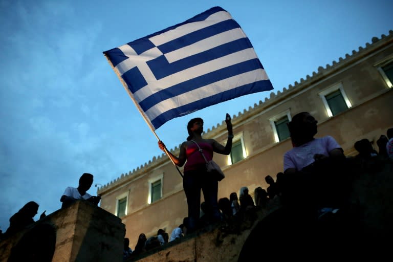 An anti-austerity protester holds a Greek flag in front of the parliament during a protest against austerity policies in Athens on June 21, 2015