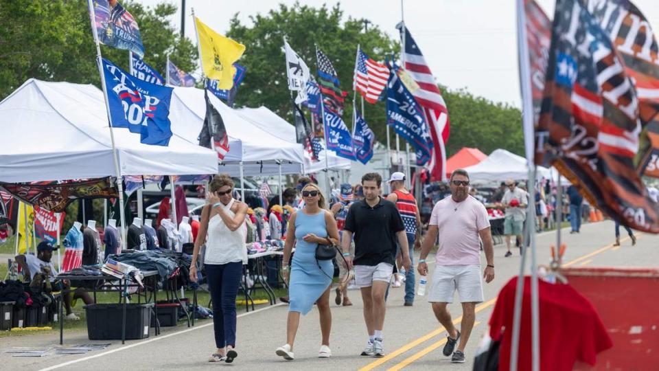 People stroll along Trask Drive, among a sea of vendors selling Trump memorabilia, prior to a rally for the former President at the Aero Center on Saturday, April 20, 2024 in Wilmington, N.C.