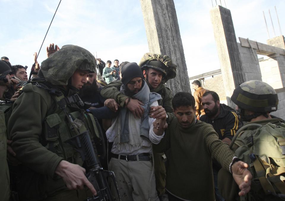 Israeli soldiers escort away a Jewish settler after he was detained by Palestinian villagers near Nablus