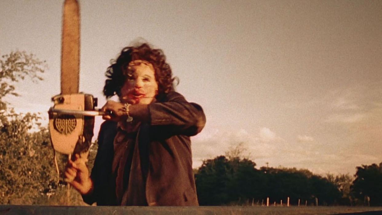 leatherface holds up a chainsaw in a scene from the texas chainsaw massacre, a good housekeeping pick for best halloween movies