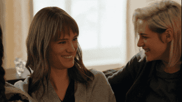 Kirsten Stewart as Abby laughing with Mackenzie Davis as Harper in "Happiest Season"