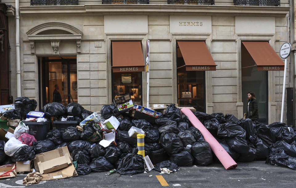 ARCHIVO - Una mujer pasa junto a basura sin recoger en París, el 20 de marzo de 2023, durante una huelga prolongada de servicios de limpieza. (AP Foto/Aurelien Morissard, Archivo)