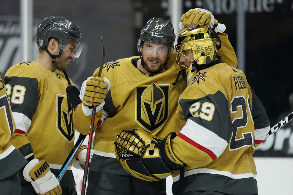 Vegas Golden Knights defenseman Shea Theodore (27) embraces goaltender Marc-Andre Fleury (29) after defeating the Arizona Coyotes in an NHL hockey game Wednesday, Jan. 20, 2021, in Las Vegas. (AP Photo/John Locher)