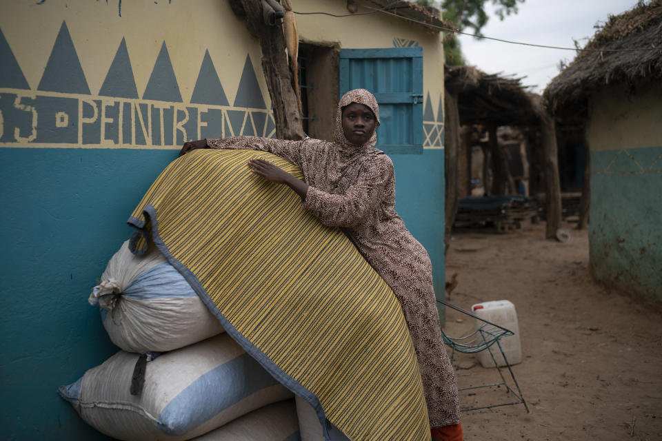 In this Nov. 26, 2018 photo, Mariama Konte, 20, stands near her home in a village near Goudiry, Senegal. Konte, who married Abdrahamane when she was 12 and he was 21, is living the consequences of the family's decision in November to mourn him after nearly four years of waiting. Friends and neighbors told them they would feel better if they went ahead with the ceremony, as five other families from the same shipwreck already had. (AP Photo/Felipe Dana)