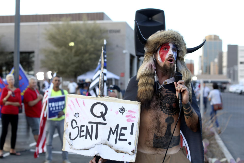 FILE - In this Nov. 5, 2020, file photo, Jacob Anthony Chansley, who also goes by the name Jake Angeli, a Qanon believer speaks to a crowd of President Donald Trump supporters outside of the Maricopa County Recorder's Office where votes in the general election are being counted, in Phoenix. Some followers of the QAnon conspiracy theory are now turning to online support groups and even therapy to help them move on, now that it's clear Trump's presidency is over. (AP Photo/Dario Lopez-Mills, File)