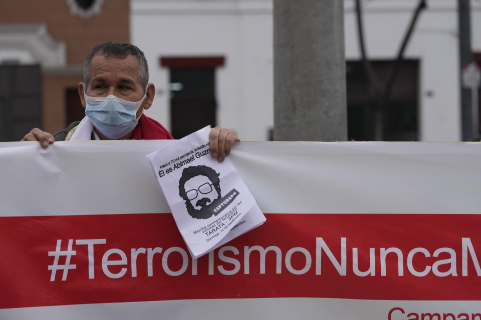 A man helps hold up a banner with a hashtag that reads in Spanish; "Terrorism never again" as he joins others outside the anti-terrorism directorate to celebrate the death of Abimael Guzman, founder and leader of the Shining Path guerrilla movement, in Lima, Peru, Saturday, Sept. 11, 2021. Guzman who was captured in 1992, died on Saturday in a military hospital after an illness, the Peruvian government said. He was 86. (AP Photo/Martin Mejia)