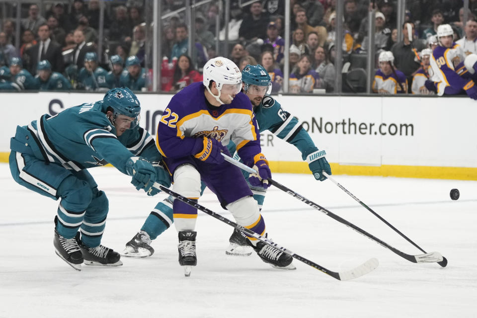 Los Angeles Kings' Kevin Fiala (22) is defended by San Jose Sharks' Scott Harrington (4) and Erik Karlsson (65) during the second period of an NHL hockey game Saturday, Dec. 17, 2022, in Los Angeles. (AP Photo/Jae C. Hong)