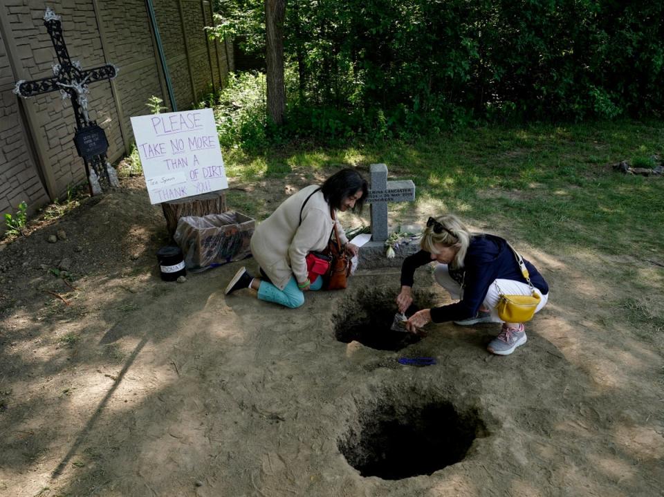 People collect dirt from the gravesite of Sister Wilhelmina Lancaster at the Benedictines of Mary, Queen of Apostles abbey Sunday, May 28, 2023, near Gower, Mo. Hundreds of people visited the small town in Missouri this week to see the nun’s body that has barely decomposed since 2019 (AP Photo/Charlie Riedel) (AP)