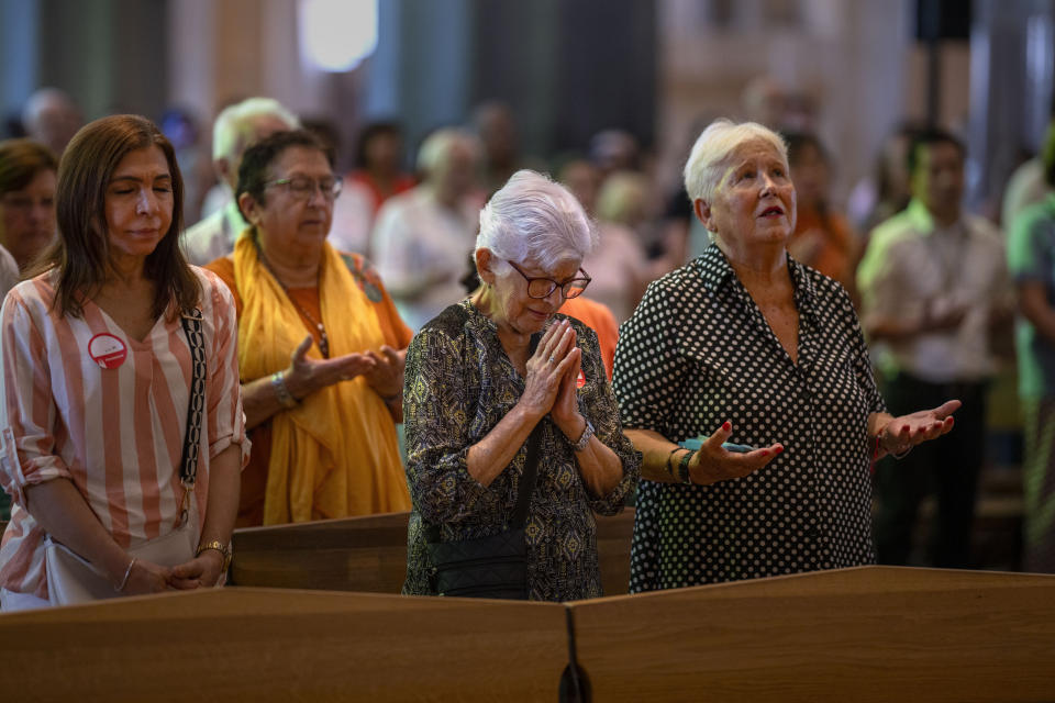 Worshippers pray during a Mass in the Sagrada Familia basilica in Barcelona, Spain, Sunday, July 9, 2023. With tourism reaching or surpassing pre-pandemic levels across Southern Europe this summer, iconic sacred sites struggle to find ways to accommodate both the faithful who come to pray and millions of increasingly secular visitors attracted by art and architecture. (AP Photo/Emilio Morenatti)