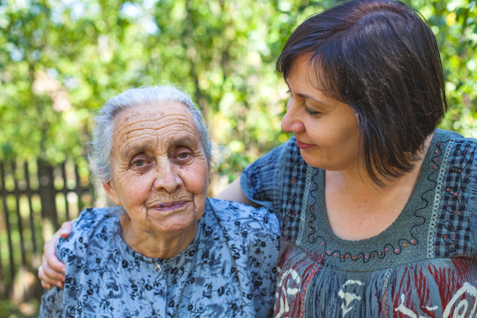 Middle aged woman posing with her sick old mother in the garden