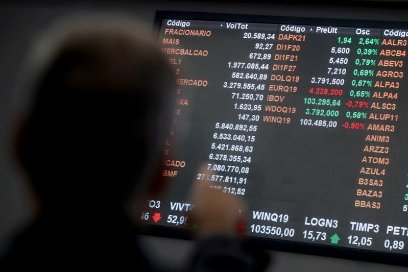 FILE PHOTO: Currency exchange rates of euro and the U.S. dollar are seen on an electronic board as a man points at it on the floor of Brazil's B3 Stock Exchange in Sao Paulo