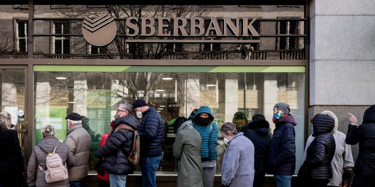 People queue outside a branch of Russian state-owned bank Sberbank to withdraw their savings and close their accounts following Russia's attack on Ukraine.