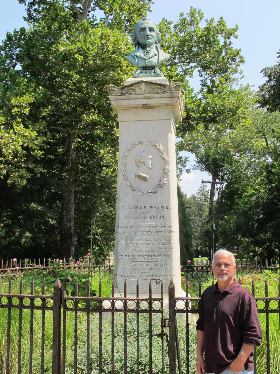 In this Tuesday, Aug. 20, 2013 photo, Gary Berton, former president of the Thomas Paine National Historical Association, stands next to a Paine monument in New Rochelle, N.Y. The association's once-endangered collection of about 300 Paine-related pieces is the cornerstone of a new Institute for Thomas Paine Studies at Iona College. (AP Photo/Jim Fitzgerald)
