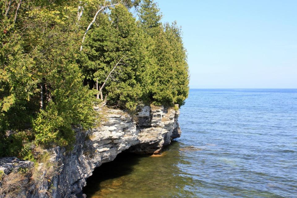 White, blocky cliffs that are part of the Niagara Escarpment line the Lake Michigan shoreline at Cave Point County Park in Door County.