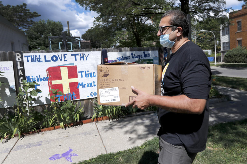 ROOH owner Manish Mallick delivers some of the 450 meals from his Indian restaurant for I Grow Chicago, in the Englewood neighborhood of Chicago on Monday, July 13, 2020. Mallick is a regular on the Southside now, and a popular one who regularly arrives bearing food. "Thank you, sugar, for the meals. They're so delicious!" one woman recently shouted to Mallick outside a South Side YWCA. He recorded her response on his phone so he could share it with his staff. (AP Photo/Charles Rex Arbogast)