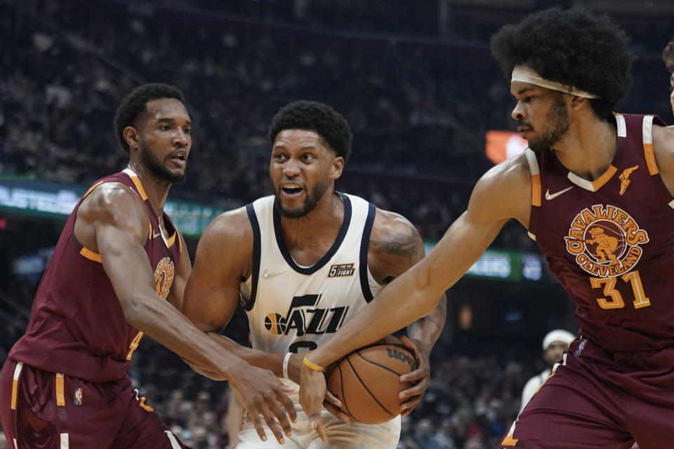 Utah Jazz's Rudy Gay, center, drives to the basket against Cleveland Cavaliers' Evan Mobley, left, and Cleveland Cavaliers' Jarrett Allen in the first half of an NBA basketball game, Sunday, Dec. 5, 2021, in Cleveland. (AP Photo/Tony Dejak)