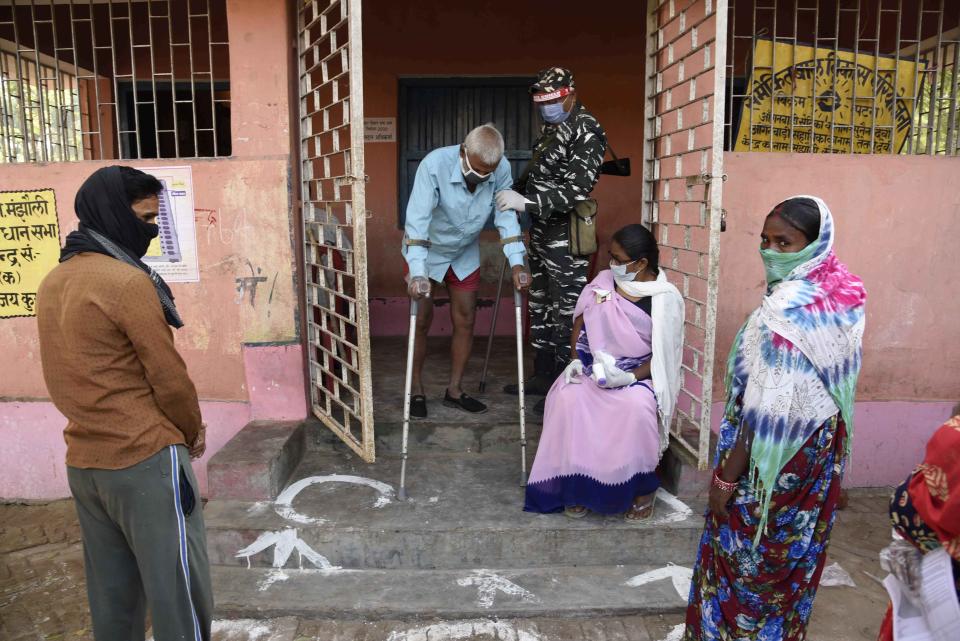 A security officer wearing a face shield as a protective measure against the coronavirus helps an elderly voter exit a polling station, during the first phase of state elections at Paliganj, in the eastern Indian state of Bihar, Wednesday, Oct. 28, 2020. With an overall declining coronavirus positive trend, Indian authorities decided to hold the first state legislature election since the outbreak of COVID-19. People began voting Wednesday in the country’s third largest state Bihar with of a population of about 122 million people. (AP Photo/Aftab Alam Siddiqui)