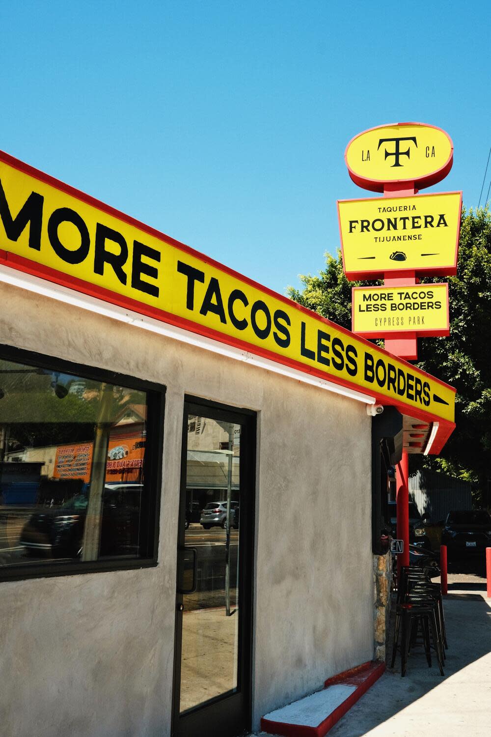 An exterior of Cypress Park's Taquería Frontera. The yellow, black and red signage reads: MORE TACOS LESS BORDERS