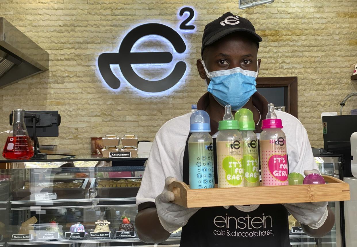 A waiter poses with a tray of baby bottles that he brought out from storage, at Einstein Cafe in Dubai, United Arab Emirates, Sunday, March 14, 2021.