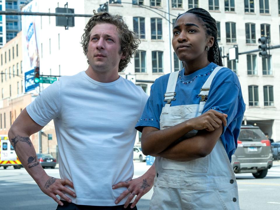 jeremy allen white and ayo edebiri in the bear, standing with puzzled expressions on their faces on a street