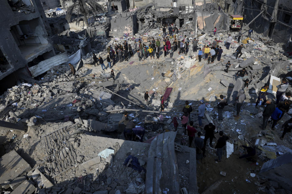 FILE - Palestinians look at the destruction of the Al-Gatshan family building after an Israeli strike in Nusseirat refugee camp, central Gaza Strip, on Dec. 18, 2023. After 11 weeks of war in Gaza, the Israeli military campaign against Hamas now sits among the deadliest and most destructive in history. The Palestinian death toll is approaching 20,000 and satellite data shows that one-third of structures across the tiny enclave have been destroyed. (AP Photo/Adel Hana, File)