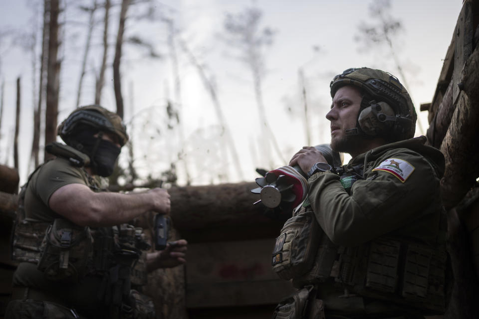 A Ukrainian serviceman from the Azov brigade known by call sign Chaos, right, carries mortar shell, while he waits for a command to fire, at positions of 122 mm HM 16 mortar around one kilometer away from Russian forces on the frontline in Kreminna direction, Donetsk region, Ukraine, Friday, April 12, 2024. (AP Photo/Alex Babenko)