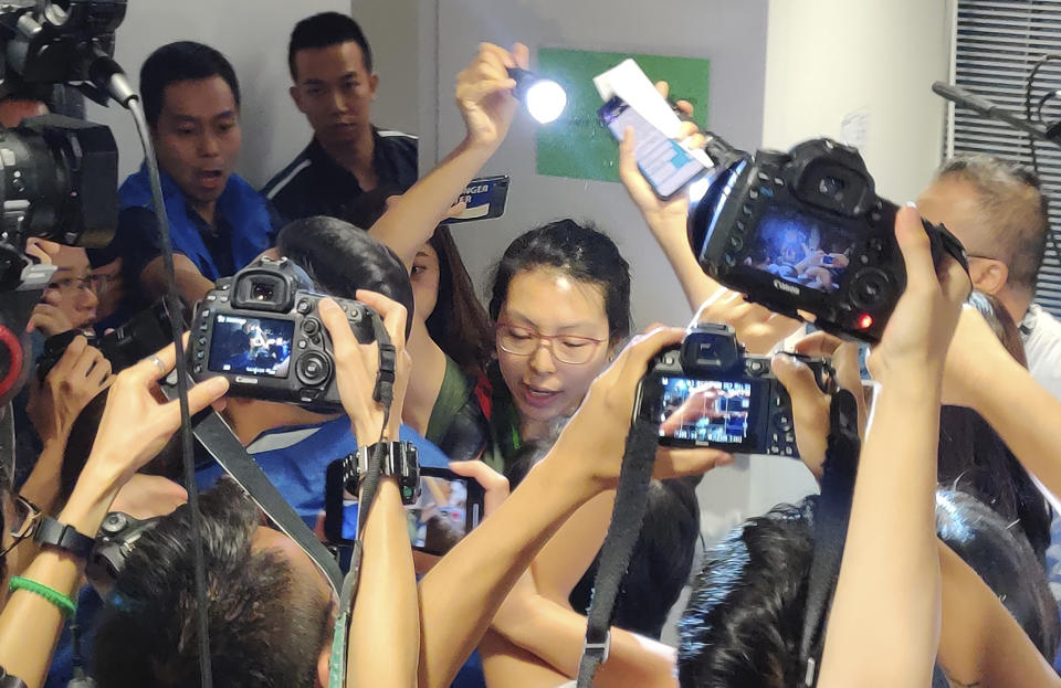 An unidentified alleged reporter, center, raises a flashlight to read a statement during a police news conference in Hong Kong, Monday, Oct. 28, 2019. The unidentified alleged reporter has disrupted the news conference to protest what she calls the escalating violence by officers against journalists covering the city's pro-democracy protests. (AP Photo/Kelvin Chan)