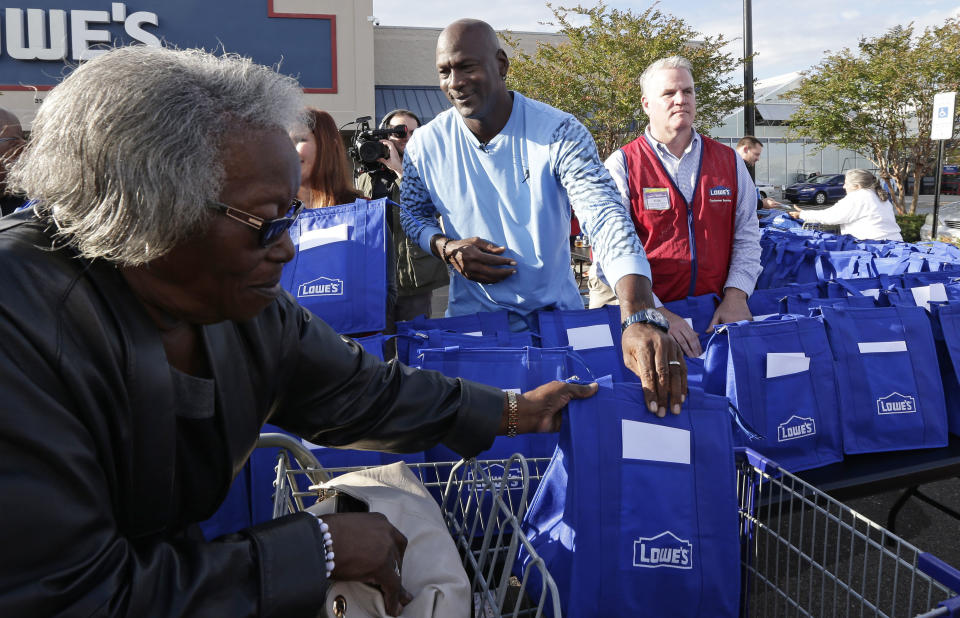 Charlotte Hornets owner Michael Jordan gives a bag of food for Thanksgiving to a woman while greeting members of the community in Wilmington, N.C., Tuesday, Nov. 20, 2018. (AP Photo/Gerry Broome)